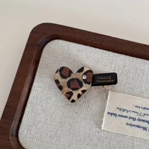 Close-up of cute leopard print heart hair clip with sparkling rhinestone and metal duckbill.