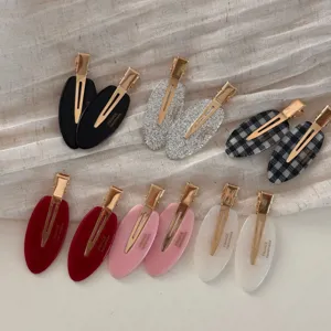 Detail shot of stylish oval hair clips with golden duckbill design in various chic colors.