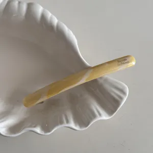 Vue détaillée de la pince à cheveux fine en acétate, barrette élégante marbrée jaune de près.
