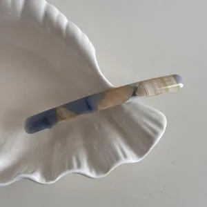 Pince à cheveux élégante en acétate avec motif marbré, design minimaliste pour coiffures.