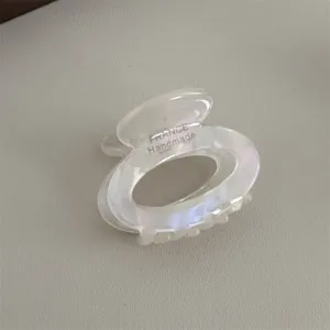 Detailed view of small transparent acetate hair claw clip, compact oval design with teeth grip.