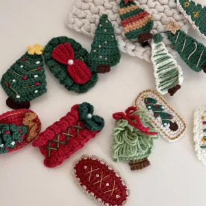 Detailed shot of handmade crochet Christmas hair clips featuring cute trees and bows with pearls.