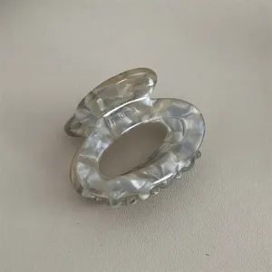 Close-up detail of small acetate hair claw clip with unique marbled pattern and glossy finish.