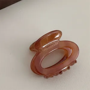 Close-up detail of a retro amber acetate hair claw clip, featuring handmade French style finish.