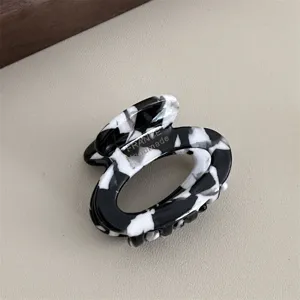 Black and white acetate small oval hair claw clip, retro french style hair accessory detail.