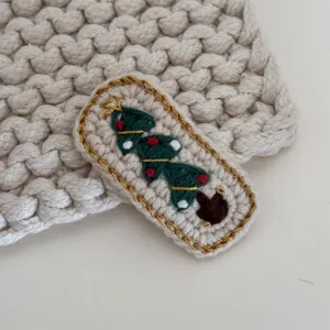 Handcrafted crochet Christmas tree hair clip detail, cute knitted hair accessory, cozy texture.