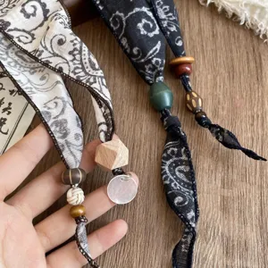Vintage paisley ribbon hair scarf with wooden beads and shell pendant detail close up shot