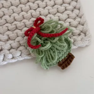 Detailed close-up shot of handmade crochet Christmas tree hair clip, sweet knit design.