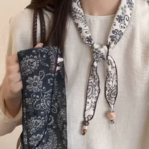Detail shot of retro paisley neck scarf with wooden beads, stylish decorative accessory.