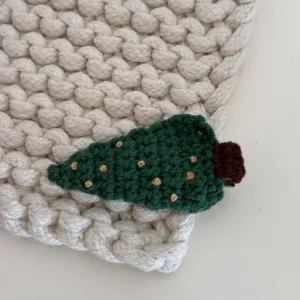 Detailed shot of cute crochet Christmas tree hair clip, handmade wool fabric side clip.