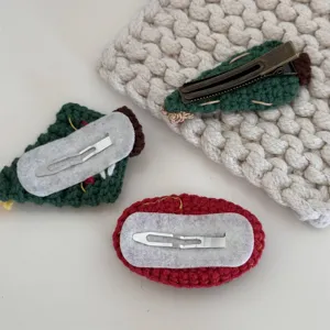 Handmade Christmas crochet hair clips detail view showing secure metal snap barrettes and felt backing.