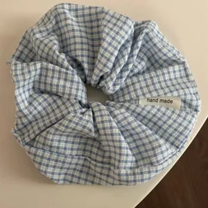 Blue and white gingham hair scrunchie detail view, soft fabric texture with handmade label.