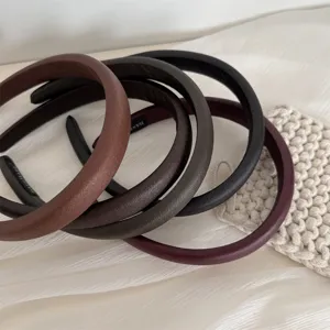 Detailed close-up of multi-color padded leather headbands arranged softly on white fabric.