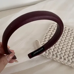 Detailed view of elegant dark red wide padded headband, soft texture with handmade label.