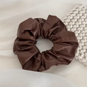 Detailed view of a soft brown leather scrunchie, elegant and chic hair tie for daily hairstyles.