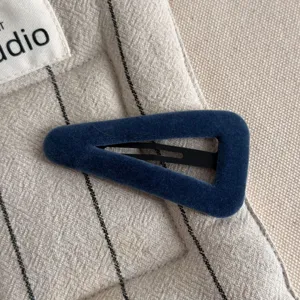 Close-up detail of dark blue velvet triangle hair clip, soft texture and chic side clip design.