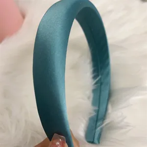 Dettaglio della fascia per capelli in raso verde petrolio con tessuto liscio e design semplice.