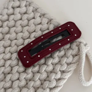 Detailopname van bordeauxlederen haarklem met polkadots, elegante pony haarspeld voor damesstijl.