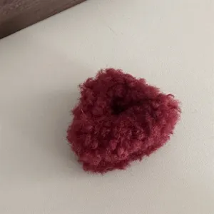 Detailed view of a cute dark red fluffy hair claw clip, soft plush styling accessory.