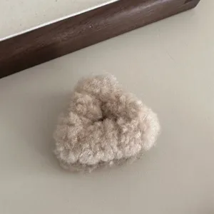 Detailed close-up of a cute plush fluffy triangular hair claw clip in soft beige tone.