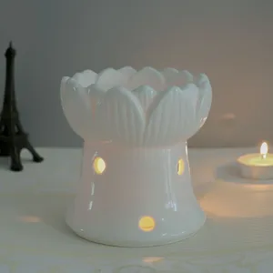 Primo piano di bruciatore di oli essenziali in ceramica bianca di loto con candela accesa.
