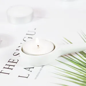 Ceramic tea light candle holder detail view featuring a white ceramic handle and burning wax.