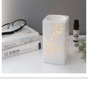 Détail de brûleur d'huile essentielle creux en céramique blanche, motif floral élégant.