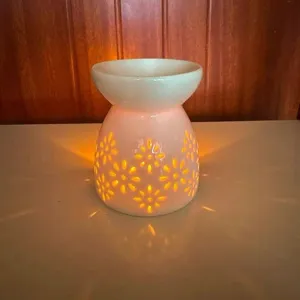 Vista di dettaglio del bruciatore per oli in ceramica con motivo floreale e calda luce.