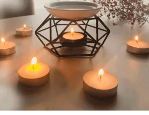 Detalle de quemador de aromas de hierro geométrico con plato de cerámica y velas para spa en casa.