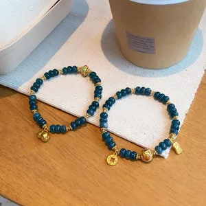 Detailed view of Chinese retro blue jadeite beaded bracelet with gold gourd and wealth charms.