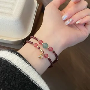 Nahaufnahme eines filigranen zweilagigen Edelstein-Perlenarmbands mit goldenem Anhänger.