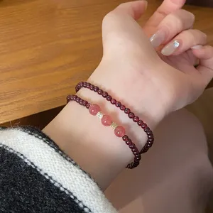 Nahaufnahme des zarten doppelten Granat- und Rosenquarz-Perlenarmbands am Handgelenk.