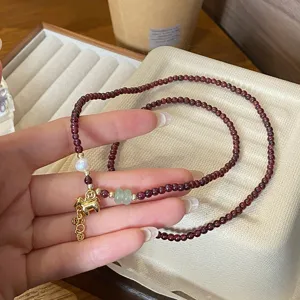 Detailansicht des Granatperlenarmbands mit doppelter Wicklung und Goldpferd-Anhänger.