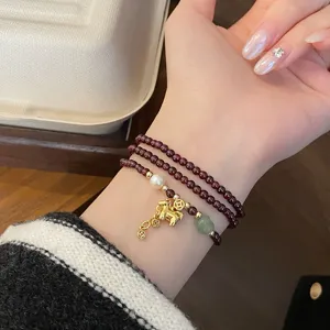 Nahaufnahme des Retro Granat Perlen Armbands mit goldenem Pferd Anhänger und Perlen.