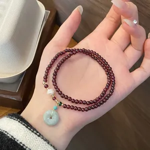 Nahaufnahme Detail des eleganten doppelt gewundenen Granat Perlenarmbands mit Anhänger.