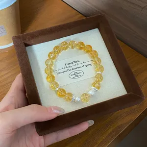 Bracelet de perles et cristaux jaunes dans une boîte à bijoux en velours marron, chic.