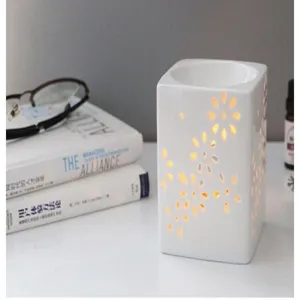 Vue détaillée du brûleur d'huiles essentielles en céramique, design floral ajouré, lumière douce.