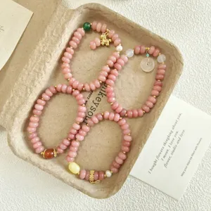 Gros plan détaillé du bracelet de perles abaque en quartz rose doux avec de jolis breloques dorées.