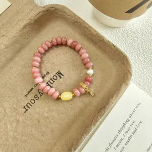Détail de bracelet en perles abaque de quartz rose, ton pêche doux et charmant pendentif doré.