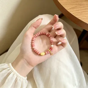 Gros plan sur le joli bracelet de perles en quartz rose avec perle élégante et pendentif doré.