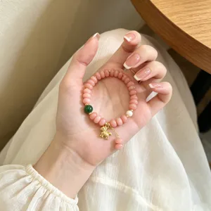 Détail en gros plan d'un bracelet de perles de quartz rose doux avec breloques dorées.