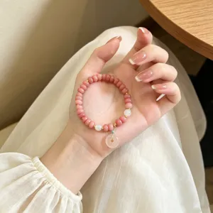 Gros plan détaillé d'un doux bracelet de perles abaque en quartz rose avec pendentif.