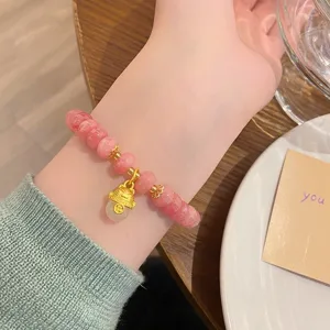 Gros plan détaillé du bracelet de perles en quartz rose avec un charmant chat doré mignon.