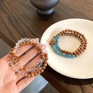Close-up detail of double-layer crystal and wooden bead bracelet with floral charm.