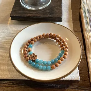 Detail shot of retro double-layer sandalwood and blue bead bracelet with a wooden flower charm.
