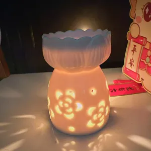 Detailed shot of white ceramic aromatherapy burner with floral cutout design, emitting warm glow.