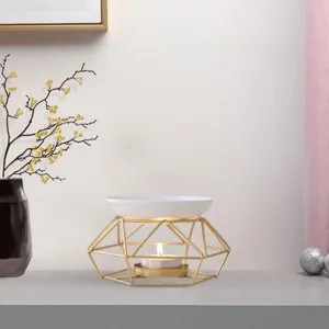 Gold iron aromatherapy burner detail showing geometric metal stand and white ceramic bowl.