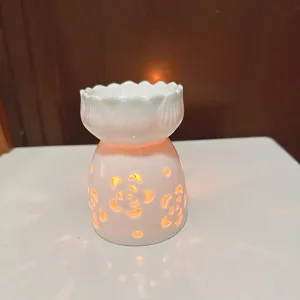 Ceramic oil burner detail view, white lotus candle holder with hollow floral glowing base.