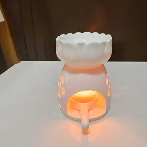 Close up detail of white ceramic lotus oil burner with warm glowing light inside.