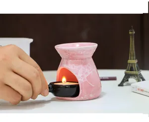 Ceramic essential oil burner detail shot showing pink crackle glaze design with candle lit inside.